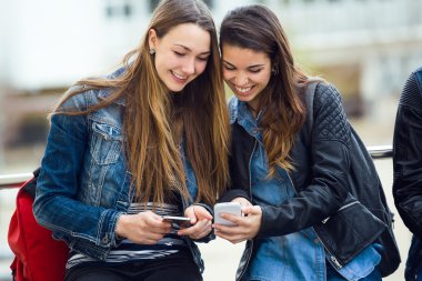 Cep telefonuyla sokakta iki güzel öğrenci.