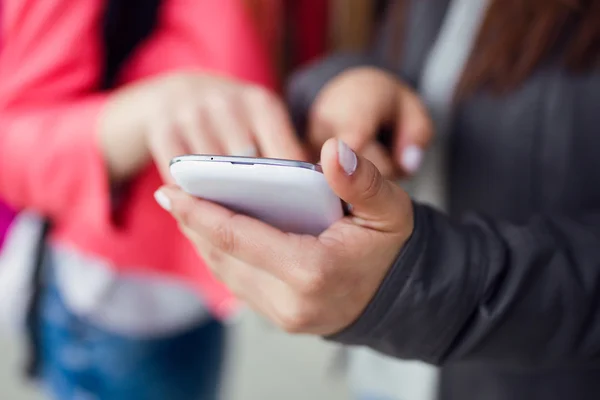 Two beautiful students using mobile phone in the street. — Stock Photo, Image