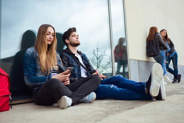 Groep studenten met plezier met smartphones na klasse. — Stockfoto