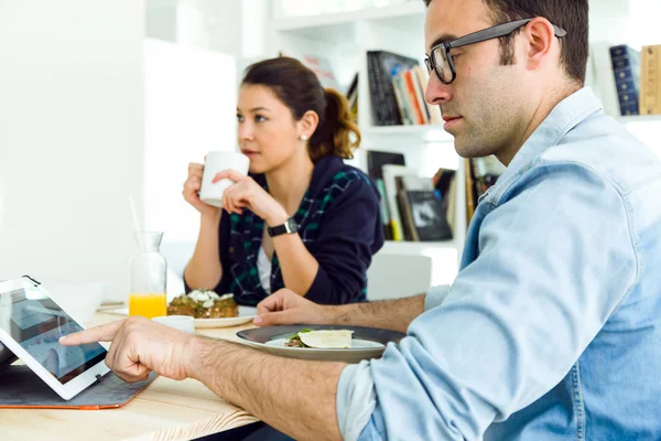 Ungt par njuter av frukost och arbeta hemma. — Stockfoto