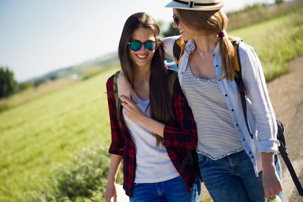 Twee mooie dames wandelaars lopen op de weg. — Stockfoto