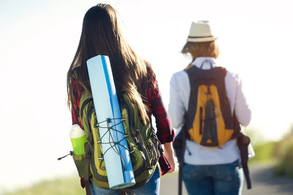 Two beautiful ladies hikers walking on the road. — Stock Photo, Image