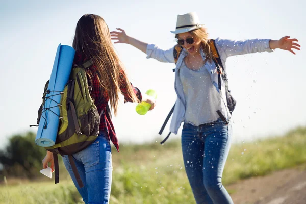 Twee mooie dames wandelaars lopen op de weg. — Stockfoto