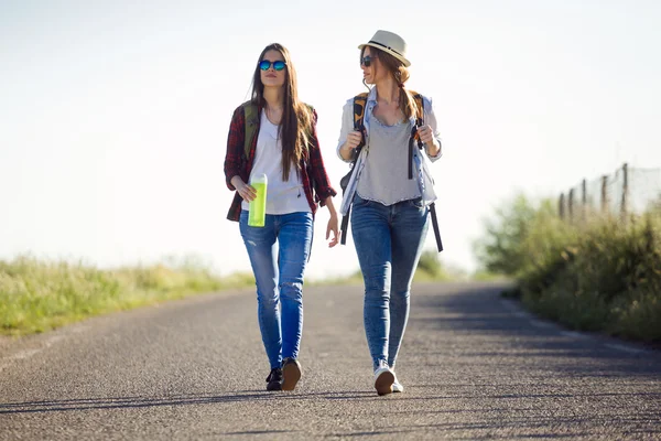 Twee mooie dames wandelaars lopen op de weg. — Stockfoto