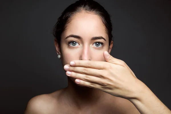 Beautiful young woman covering her mouth with hand. Isolated. — Stock Photo, Image