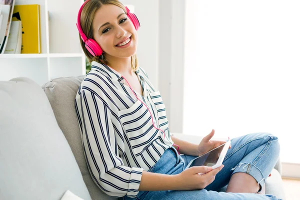 Schöne junge Frau hört Musik mit digitalem Tablet. — Stockfoto