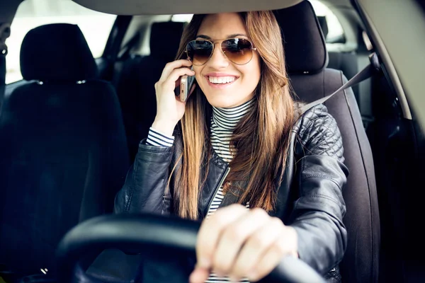 Hermosa mujer joven usando su teléfono móvil en el coche . — Foto de Stock