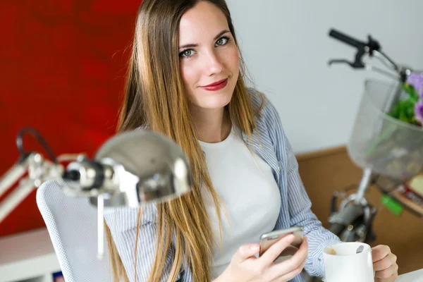 Bella giovane donna che utilizza il suo telefono cellulare in ufficio . — Foto Stock