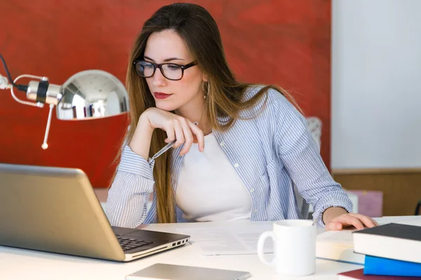 Hermosa mujer joven que trabaja con el ordenador portátil en su oficina . — Foto de Stock