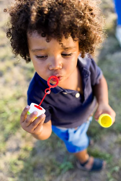 Afro-americano bebê soprando bolhas de sabão no parque . — Fotografia de Stock