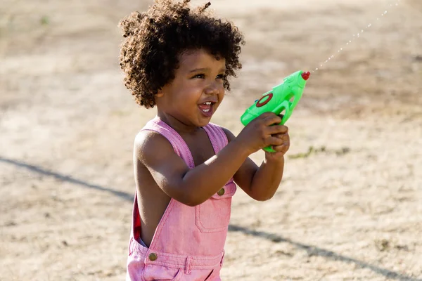 公園で水鉄砲で遊ぶアフリカ系アメリカ人の赤ちゃん. — ストック写真