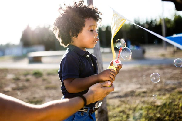 Afro-americano bebê soprando bolhas de sabão no parque . — Fotografia de Stock