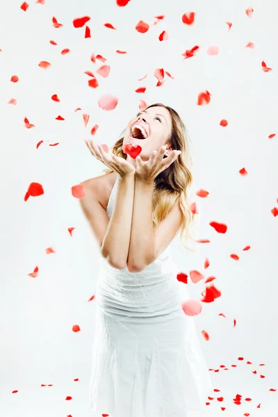Beautiful young woman under a rain of rose petals. — Stock Photo, Image
