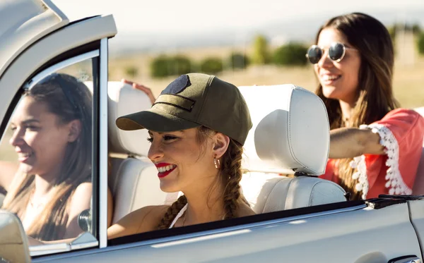 Three pretty young women driving on road trip on beautiful summe — Stock Photo, Image