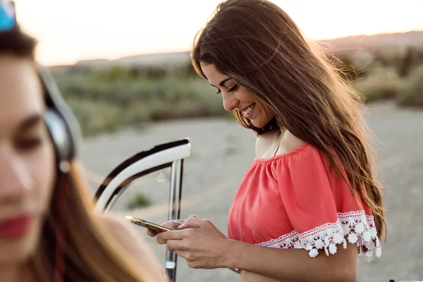 Mooie jonge vrouw met behulp van mobiele telefoon op road trip. — Stockfoto