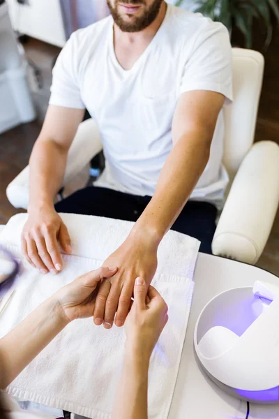 Un joven haciendo manicura en el salón. Concepto de belleza . — Foto de Stock