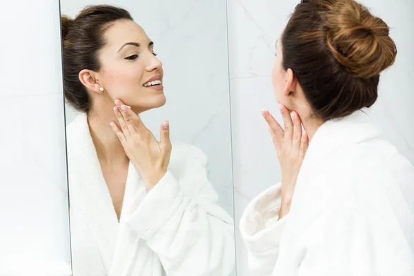 Молода жінка піклується про свою шкіру, що стоїть біля дзеркала у ванні — стокове фото