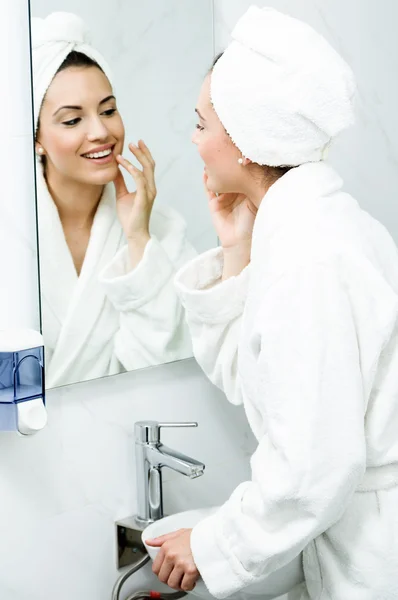 Ung kvinna omsorg av hennes hud står nära spegel i badrum — Stockfoto