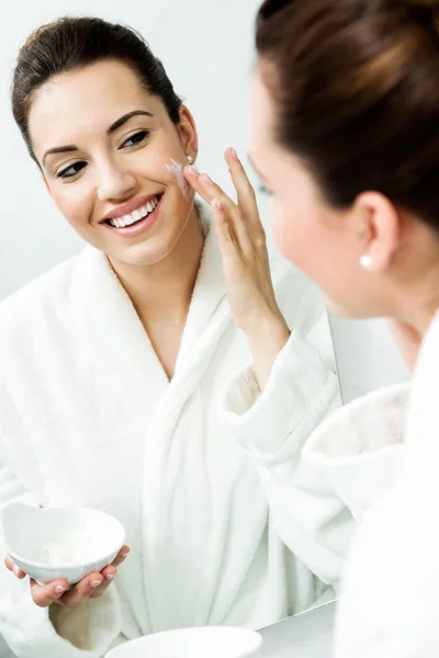 Молода жінка піклується про свою шкіру, що стоїть біля дзеркала у ванні — стокове фото