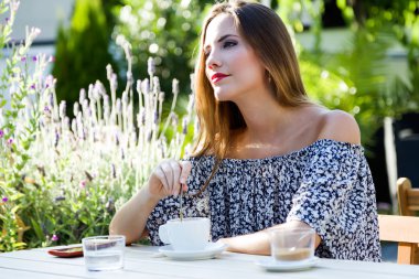 Güzel genç kadın ev bahçesinde kahve içme.