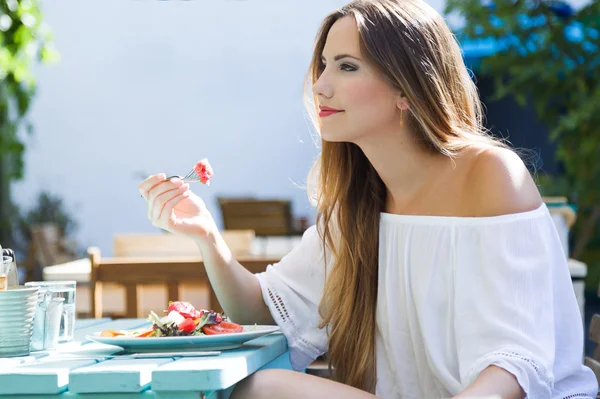 Mooie jonge vrouw salade eten in de tuin. — Stockfoto