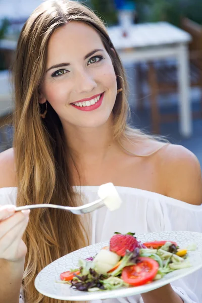 Beautiful young woman eating salad in the home garden. — Stock Photo, Image