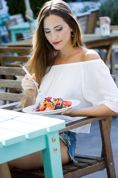 Schöne junge Frau isst Salat im heimischen Garten. — Stockfoto