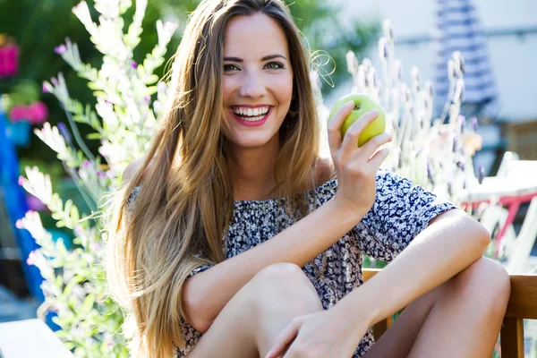 年轻漂亮的女人在家里的花园里吃一个苹果. — 图库照片