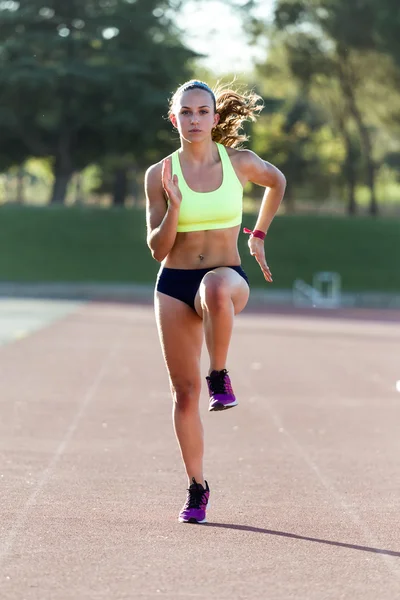 Ajuste mujer joven corriendo en el campo de pista . — Foto de Stock