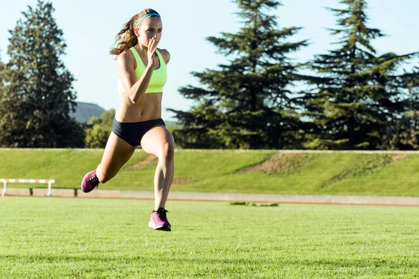 Adatto giovane donna che corre sul campo di atletica . — Foto Stock