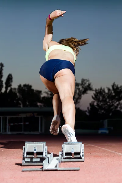 Giovane atleta femminile che lancia fuori dalla linea di partenza in una gara . — Foto Stock