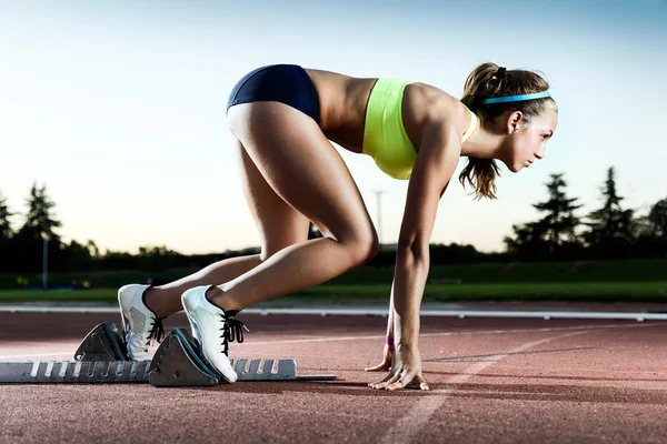 Young female athlete launching off the start line in a race. — Stock Photo, Image