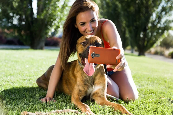 Hermosa joven con su perro usando el teléfono móvil en el str — Foto de Stock