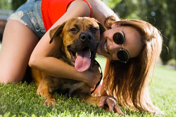 Frumoasă femeie tânără jucându-se cu câinele ei în parc . — Fotografie, imagine de stoc