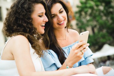 Güzel genç kadın sokakta akıllı telefonlar ile eğleniyor.