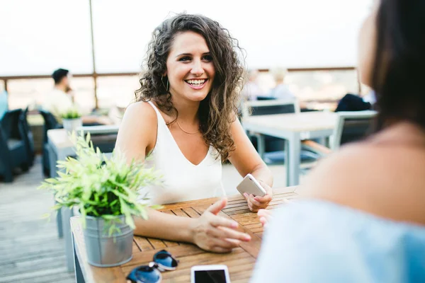 Belles jeunes femmes parlant dans une terrasse de restaurant . — Photo