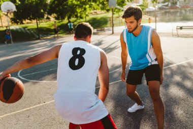 İki arkadaş sahada basketbol oynarken portresi.