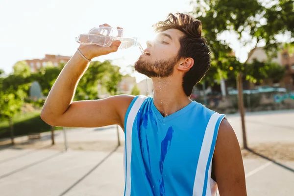 Porträt eines hübschen jungen Mannes, der vor Gericht Wasser trinkt. — Stockfoto