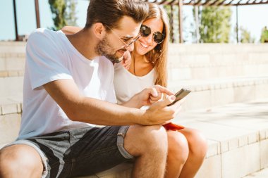 Cep telefonu kullaranarak güzel genç çift portresi.