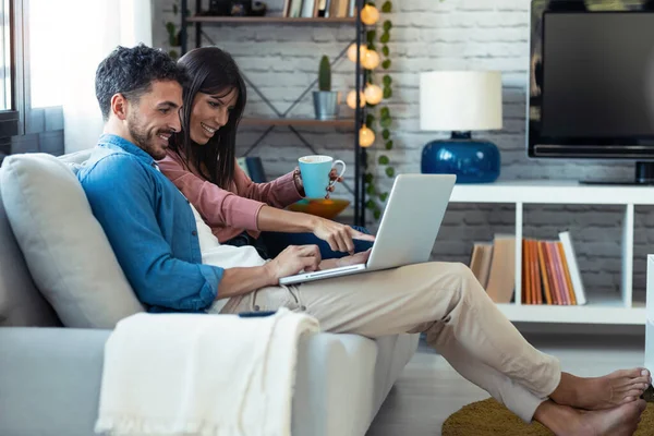 Tiro Casal Bonito Feliz Usando Computador Enquanto Sentado Sofá Casa — Fotografia de Stock