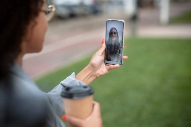 Sokakta yürürken elinde kahve tutan genç ve güzel bir iş kadınıyla görüntülü konuşma..