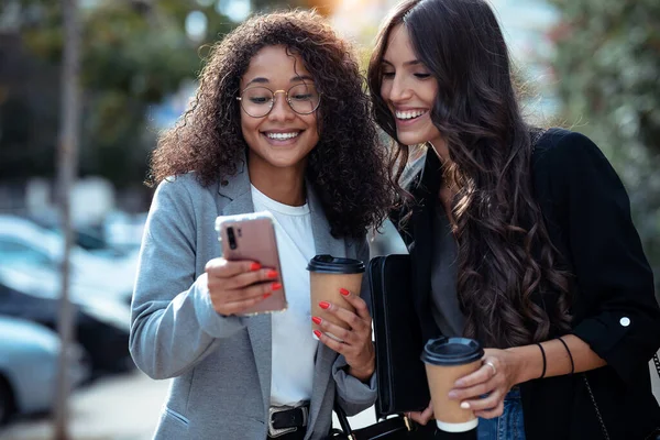 Tiro Duas Mulheres Negócios Bonitas Usando Telefone Inteligente Enquanto Bebe — Fotografia de Stock