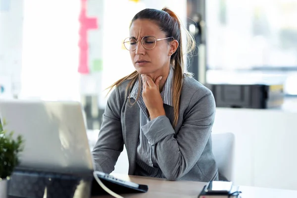 オフィスでコンピュータと働くひどい喉の痛みを持つ病気の若いビジネス女性のショット — ストック写真