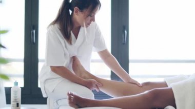 Genç ve güzel bir fizyoterapistin hamile kadının bacaklarına evde sedye ile masaj yaptığı video..