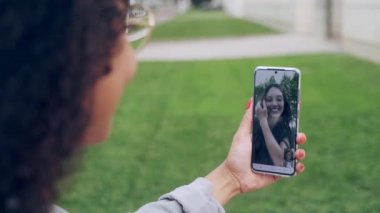 Bir kadının sokakta kahve içerken genç bir iş kadınıyla görüntülü konuşma videosu..