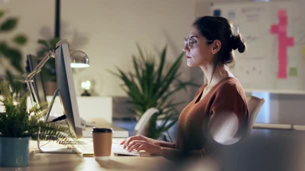 Zdjęcia Pięknej Młodej Bizneswoman Pracującej Komputerem Podczas Rozmowy Słuchawką Siedzącą — Wideo stockowe