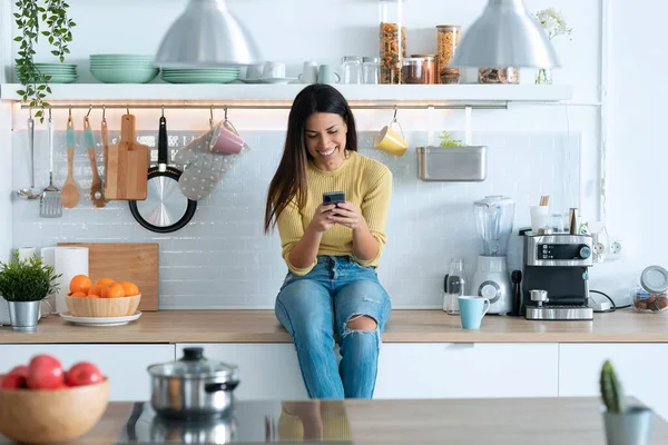 Tiro Jovem Atraente Usando Telefone Inteligente Enquanto Relaxa Sentado Cozinha — Fotografia de Stock