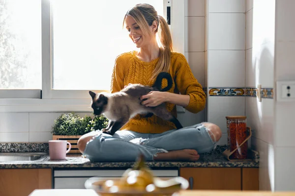 Lövés Gyönyörű Fiatal Konyhaasztalon Miközben Simogatja Macska Ölében Otthon — Stock Fotó