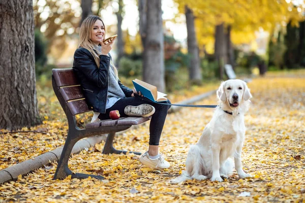 Sonbaharda Güzel Köpeğiyle Parkta Bankta Otururken Akıllı Telefonuyla Sesli Mesajlar — Stok fotoğraf