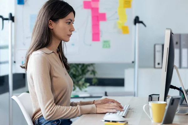 現代のスタートアップオフィスでデスクに座っている間 コンピュータで働く美しい若いビジネス女性のショット — ストック写真